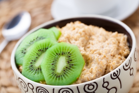 Bowl of oats porridge with kiwi on a tableの写真素材