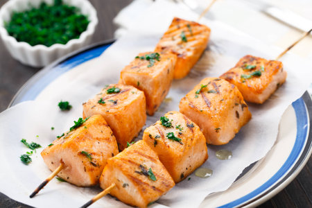 Grilled salmon skewers with parsley on a plateの写真素材