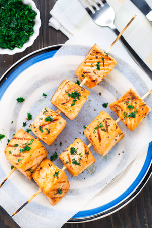 Grilled salmon skewers with parsley on a plateの写真素材