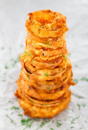 Homemade crunchy fried onion rings on a parchment. Focus on top ringsの写真素材
