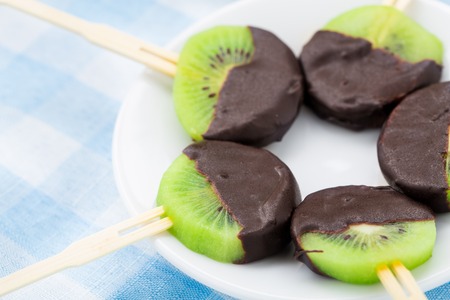 Fresh kiwi with chocolate on a stickの写真素材