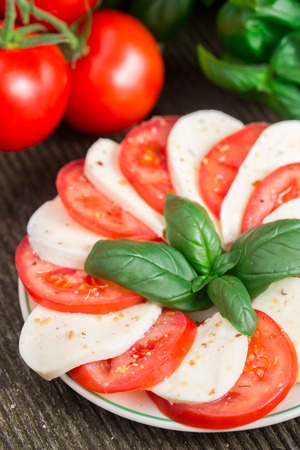 Delicious tomatoes with mozzarella and basil on a plateの写真素材