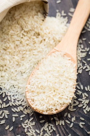 White uncooked rice in a spoonの写真素材