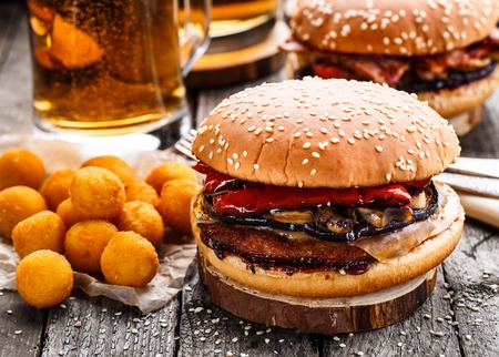 Delicious burgers with fried potato balls and beer on a rustic tableの写真素材
