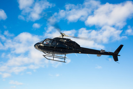 solo black helicopter in blue skies flyingの写真素材