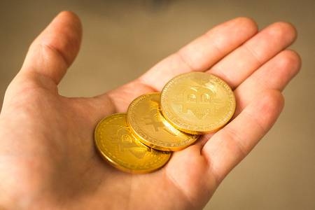 Three bitcoin coins in a hand close up goldの写真素材