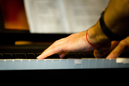 Close up male hands playing electric piano indoorsの写真素材