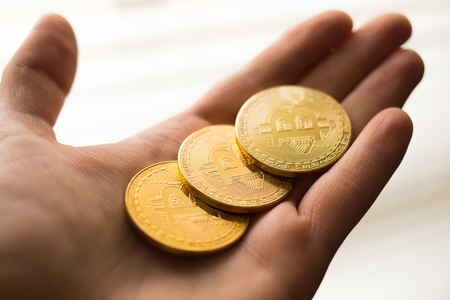 Three bitcoin coins in a hand close up goldの写真素材