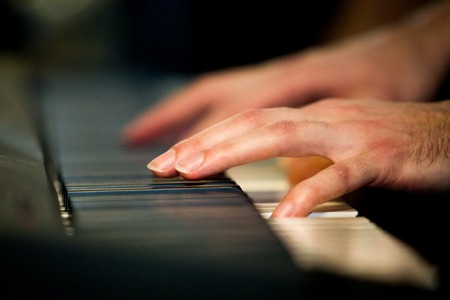 Close up male hands playing electric piano indoorsの写真素材