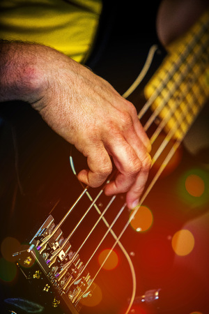 Bass guitar musician playing close up black