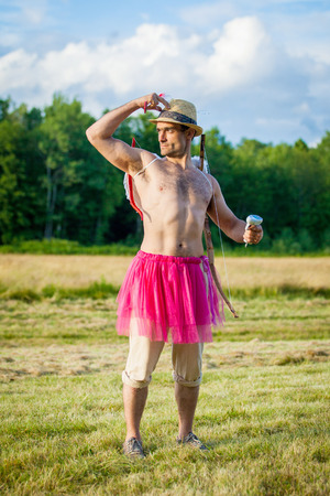White guy with wings on his back. He displays bow with arrow. Cupid on Valentine's day with pink dressの写真素材