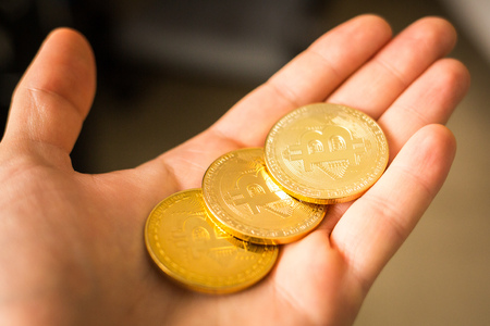Three bitcoin coins in a hand close up goldの写真素材