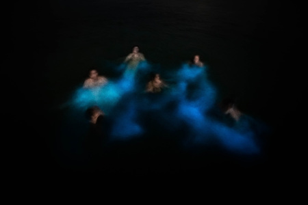 Blurred group of people swimming in glowing waters bio bayの写真素材