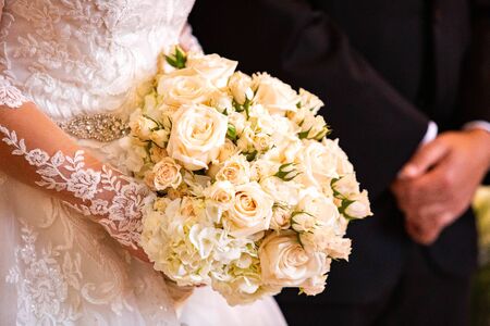 Beautiful bridal wedding bouquet isolated in hands with blurred groom togetherの写真素材