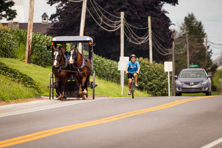 Lancaster, PA / USA - 7/4/2013: Amish man riding a retro carriage on the streetのeditorial素材
