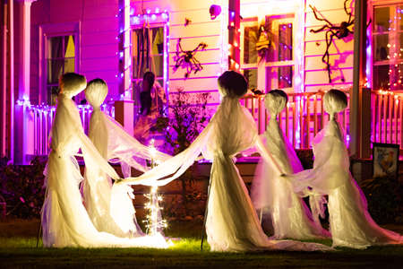 Illuminated scary Halloween house ghosts decoration at night