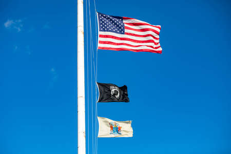 Flags of the United States, New Jersey and POW MIA in blue sunny skies