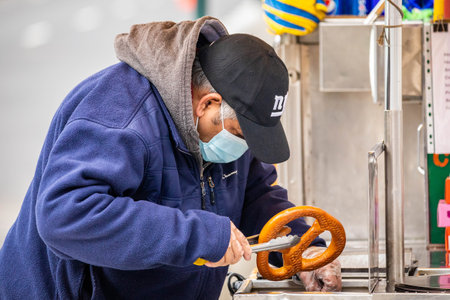 NY, NY, USA - Jan. 22, 2021: Street food seller wearing mask with pretzel at day