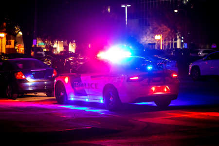 Police car with emergency lights flashing at night in city from the backの写真素材