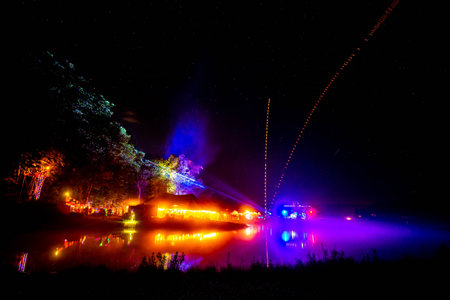 Outdoor night music party at the lake with lights and decoration tentsの写真素材