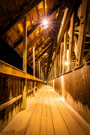 Photo of Bavarian Inn old wooden covered bridge in Frankenmuth Michigan illuminated at night with warm lights and Bavarian charm.の写真素材