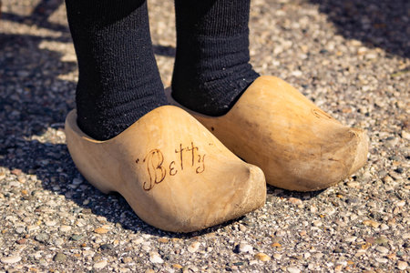 Close-up photo of legs wearing traditional Dutch wooden shoes used for walking showing cultural...