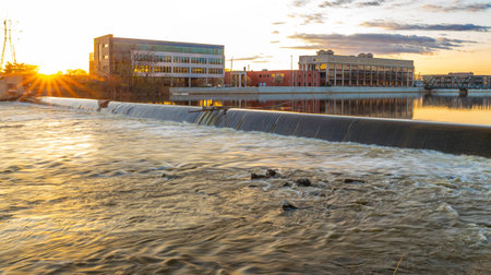 Photo of Grand Rapids Michigan cityscape with riverfront skyline glowing under golden sunset light and reflections on the water.の写真素材
