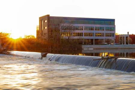 Photo of Grand Rapids Michigan cityscape with riverfront skyline glowing under golden sunset light and reflections on the water.の写真素材