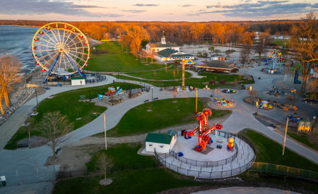 View of the Ferris wheel at Bay Beach Amusement Park in Green Bay Wisconsin during sunset, with golden sky and lakefront in the background.の写真素材