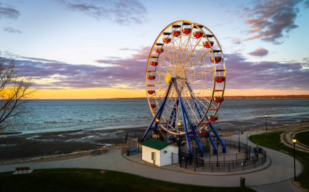 View of the Ferris wheel at Bay Beach Amusement Park in Green Bay Wisconsin during sunset, with golden sky and lakefront in the background.の写真素材