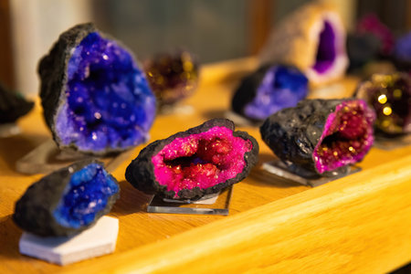 Colorful geode stones cut open to reveal sparkling quartz crystal interiors, arranged neatly on a display shelf in a rock or gift shop.の写真素材