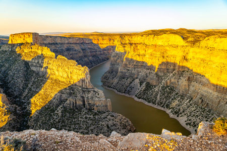 A breathtaking scenic view of a golden sunset from Devil's Canyon Overlook, casting a warm glow over...