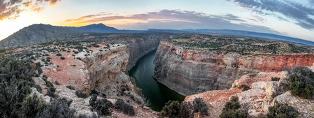 A sweeping panoramic view captures the dramatic river bend of the Bighorn River, bathed in the...