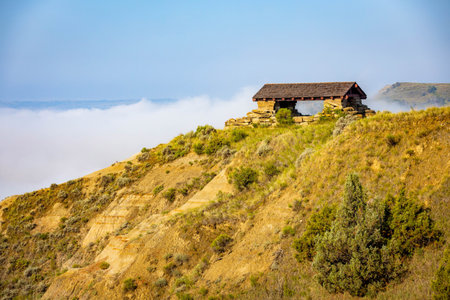 A sweeping panoramic view from the River Bend Overlook Trail at Theodore Roosevelt National Park captures the dramatic hills partially concealed by gentle morning cloudsの写真素材