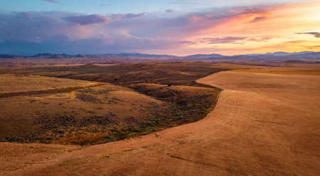 A scenic aerial view of the Montana Great Plains and prairie land at sunset, with vast open fields