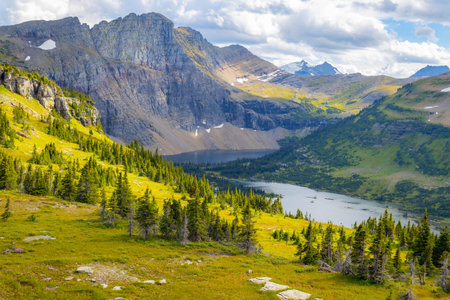 A panoramic view captures the serene Hidden Lake and its surrounding mountain range within Glacier National Parkの写真素材