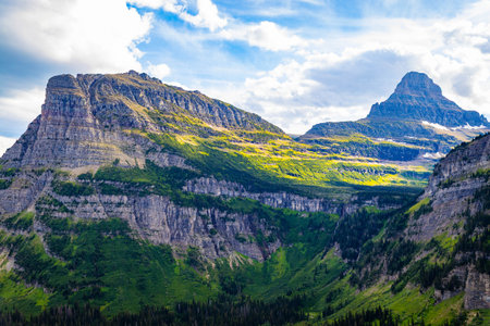 A scenic view captures a lush, green valley with majestic mountains in the background at Glacier...
