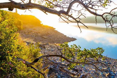 A beautiful sunrise is captured over the tranquil waters of Lake Sherburne in Glacier National Park,...