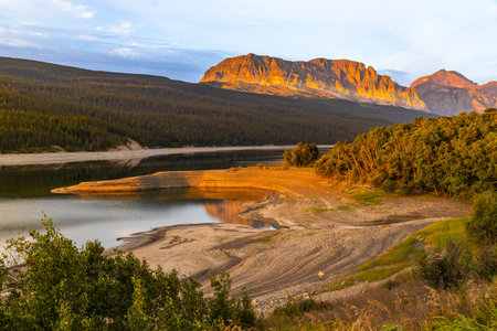 A scenic sunrise view over Lake Sherburne in Glacier National Park, with the mountains in the...