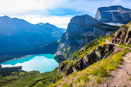 A scenic view of the turquoise Grinnell Lake seen from a hiking trail in the Many Glacier area of...