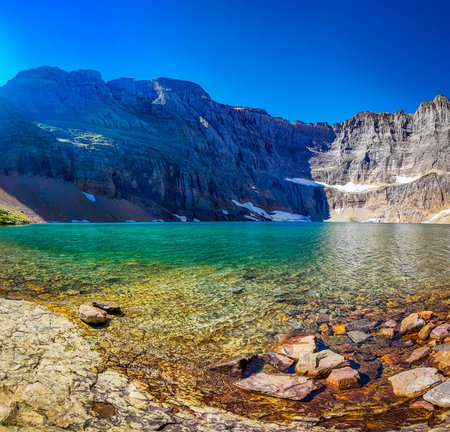 The turquoise, clear waters of Iceberg Lake are captured, showcasing the serene and beautiful body...