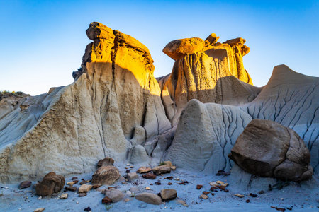 A dramatic sunset casts a golden glow over the unique hills and badlands formations of Makoshika State Parkの写真素材