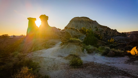 The iconic Twin Sisters rock formation silhouetted against a beautiful sunset sky at Makoshika State Parkの写真素材