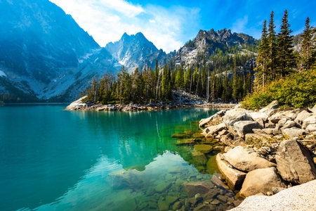 A scenic view captures the stunning, vibrant turquoise waters of Colchuck Lake, nestled within the...