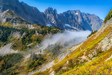 A majestic view from the Sahale Arm Trail captures thick clouds and fog beautifully settled among the rugged peaks of the Cascade Pass mountain range.の写真素材