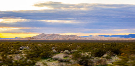 Road crosses Mojave Desert valley and mountain range at sunset in California Nevada Arizona and Utah