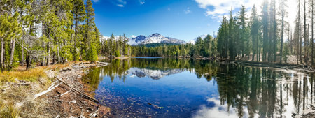 Snow covered Lassen Peak reflects in calm Manzanita Lake at Lassen Volcanic National Park California