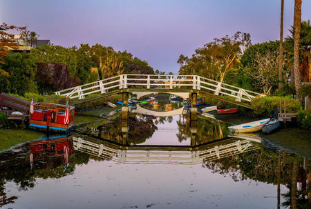 Residential buildings line the Venice Canals as warm sunset light reflects on calm water in Venice Beach California