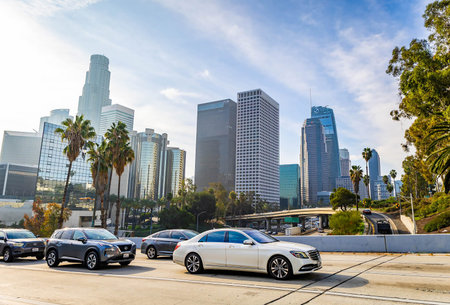 Los Angeles, CA, USA - December 03, 2025: Vehicles move along busy city streets beneath towering...