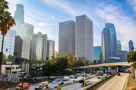 Los Angeles, CA, USA - December 03, 2025: Vehicles move along busy city streets beneath towering...